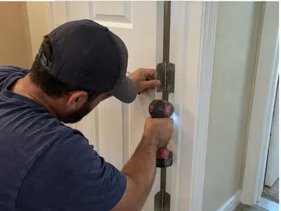 Handyman adjusting an interior door hinge with a cordless drill