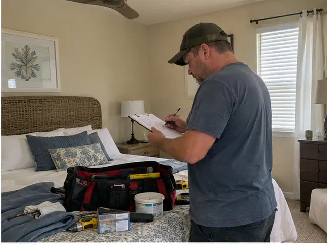 Handyman reviewing a room-by-room repair list in a furnished rental bedroom